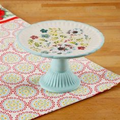 a cake plate sitting on top of a table next to a placemat and napkin