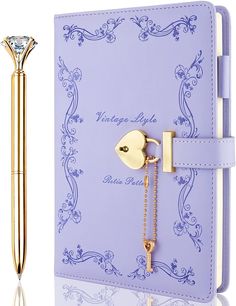 a purple notebook with a gold key attached to it and a pen next to it