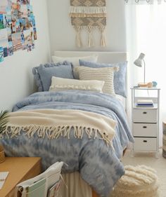 a bed with blue and white comforter in a bedroom next to a window, rugs and pictures on the wall