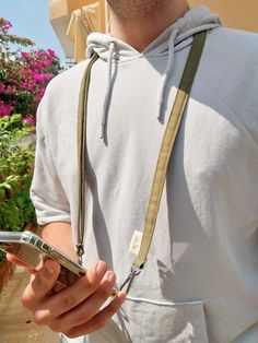 a man holding a cell phone in his right hand and wearing a lanyard around his neck