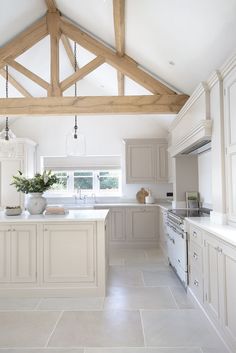 a large kitchen with white cabinets and wood beams