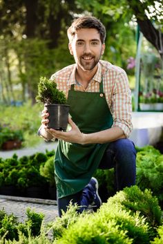 a man is holding a potted plant in his hands and smiling at the camera