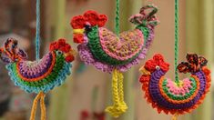 three crocheted ornaments hanging from strings in the shape of chickens and roosters