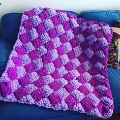 a crocheted blanket sitting on top of a blue couch next to a pillow