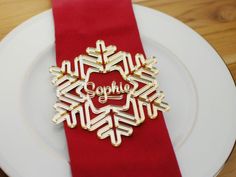 a white plate topped with a red napkin and a gold snowflake brooch