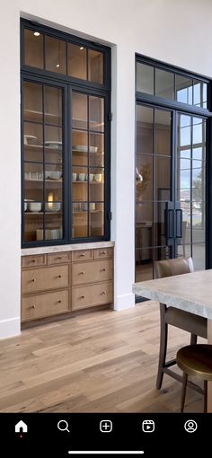 an empty room with wooden floors and glass doors on the windows, next to a dining table