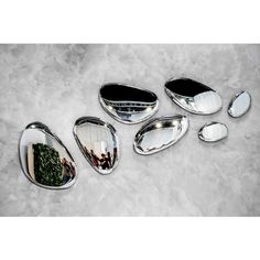 four silver spoons with different shapes and sizes are shown on a marble surface, one is