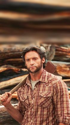 a man in plaid shirt holding an ax and standing next to wood planks on the ground