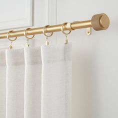 the curtain rod is attached to the side of a window with two gold rings on it