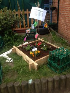 a small garden with flowers in it and a sign on the post that says,