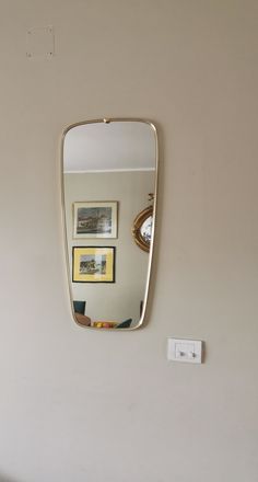 a mirror mounted to the side of a white wall next to a light switch on a wall