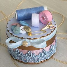 there is a small box that has some sewing supplies on top of it and thread