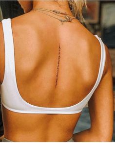 the back of a woman's white top with a tattoo on her left shoulder