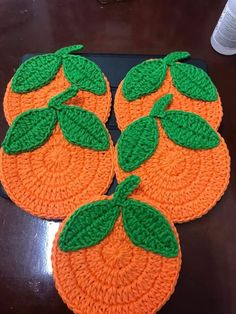 three crocheted coasters with green leaves on them sitting on top of a table