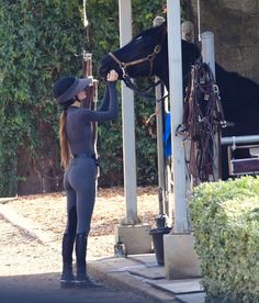 a woman in tights and boots is petting a horse