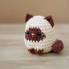 a small crocheted cat sitting on top of a wooden table