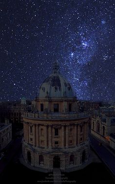 the night sky is filled with stars above an old building and some buildings in the foreground