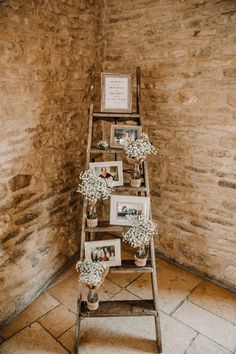 an old ladder with pictures and baby's breath flowers on it in front of a brick wall