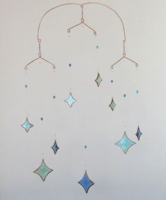 a blue and green dream catcher hanging from the ceiling with stars on it's sides