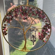 a tree with many beads hanging from it's branches in front of a window