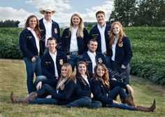 a group of young women and men posing for a photo in front of a field