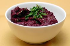 a white bowl filled with beetroot and parsley on top of a table