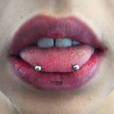 a woman's lips and nose with piercings on her tongue are seen in this image