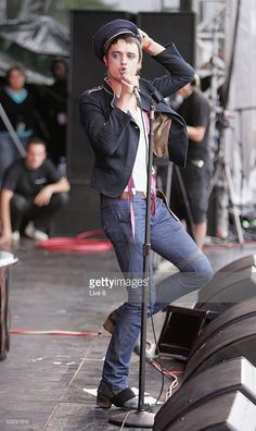 a man standing on top of a stage holding a microphone to his ear and singing