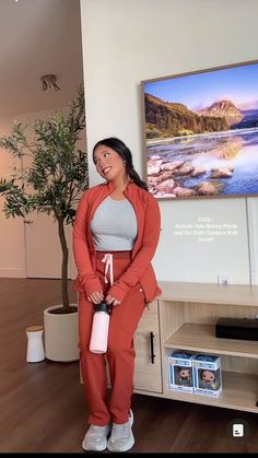 a woman standing in front of a tv holding a water bottle and looking at the camera