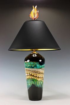 a table lamp with a black shade on it and a gold fish in the center