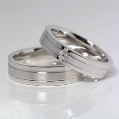 two white gold wedding bands with a diamond in the center and an invisible channel between them