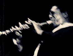 a man is playing an instrument in black and white photo, with his hands on the strings