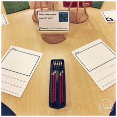 two red pencils sitting on top of a wooden table next to some writing paper