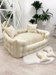 a large white couch sitting on top of a floor next to a potted plant