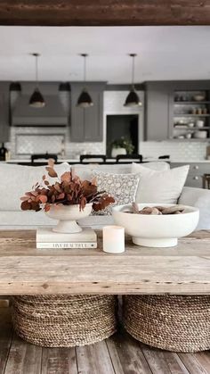 a living room filled with furniture and a wooden table topped with two white vases