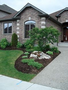 a house with landscaping in front of it and grass around the driveway area on both sides