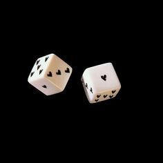 two white dices with black hearts on the sides, against a black background photo