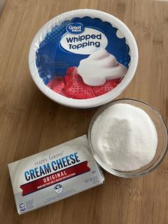 a bowl of cream cheese next to a bag of whipped topping on a wooden table