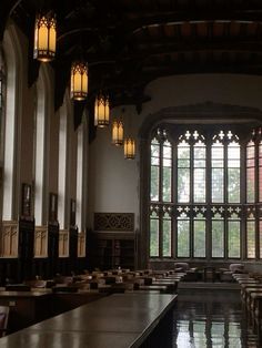 an empty room with tables and lamps in front of large windows at the end of it