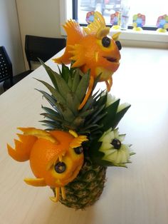 a pineapple decorated with oranges and fish heads sitting on top of a table