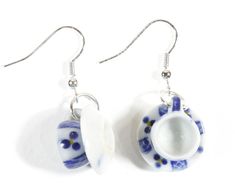 pair of blue and white glass earrings with silver earwires hanging from hooks on white background