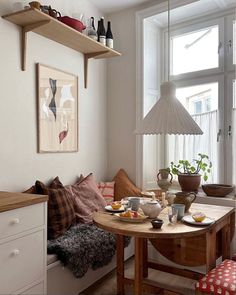 a table with food and drinks on it in front of a window next to a couch