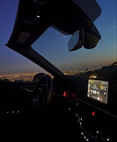 the view from inside a car looking out over a city at night with lights on