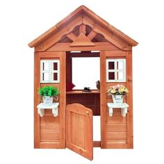 a wooden dollhouse with two doors open and flowers in the potted planter