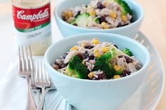 two blue bowls filled with rice, broccoli and black beans next to a can of campbell's soup