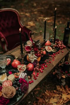 a wooden table topped with candles and fruit