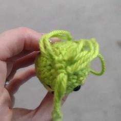 someone is holding a crocheted green object in their hand and it looks like an octopus