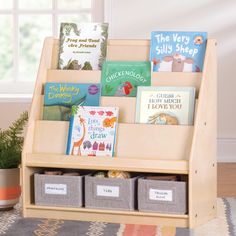 children's books are displayed on a wooden book stand in front of a window