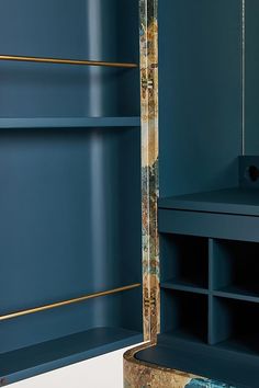 a blue bookcase with gold trim around the edge and shelves in front of it