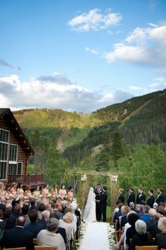 a bride and groom are standing at the end of their wedding ceremony with mountains in the background